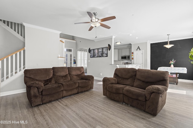 living room with hardwood / wood-style flooring, ornamental molding, and ceiling fan