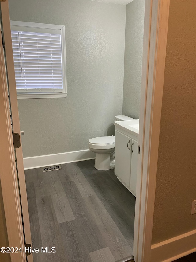 bathroom with hardwood / wood-style floors, vanity, and toilet