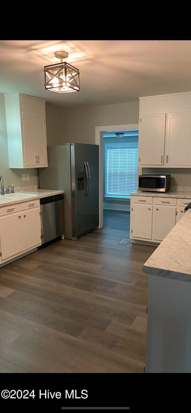 kitchen with a textured ceiling, stainless steel appliances, sink, white cabinets, and dark hardwood / wood-style floors