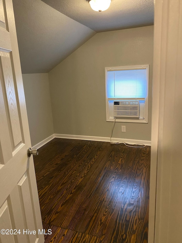 additional living space with dark hardwood / wood-style floors, cooling unit, a textured ceiling, and vaulted ceiling