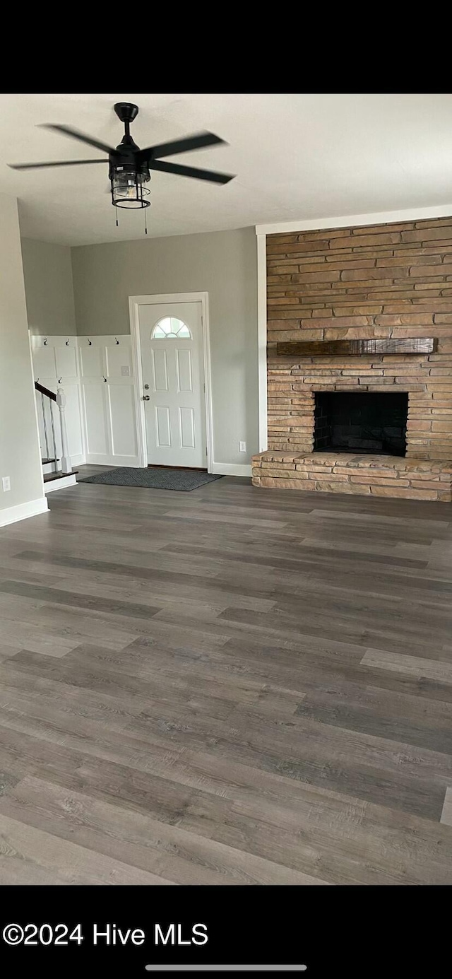 unfurnished living room with a fireplace, ceiling fan, and dark wood-type flooring