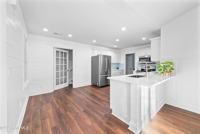 kitchen featuring white cabinetry, sink, dark hardwood / wood-style floors, kitchen peninsula, and appliances with stainless steel finishes