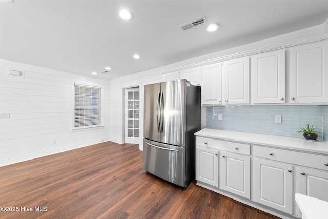 kitchen featuring white cabinetry, dark wood-type flooring, stainless steel refrigerator, and tasteful backsplash