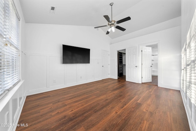 unfurnished bedroom featuring ceiling fan, dark hardwood / wood-style floors, ensuite bathroom, lofted ceiling, and a walk in closet