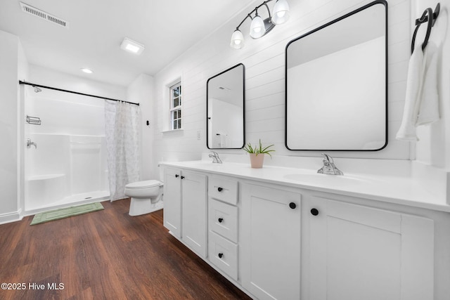 bathroom featuring vanity, toilet, wood-type flooring, and walk in shower