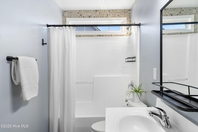 full bathroom with toilet, shower / bathtub combination with curtain, a healthy amount of sunlight, and sink