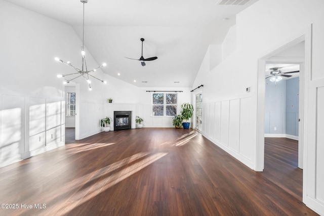 unfurnished living room featuring dark hardwood / wood-style floors, ceiling fan with notable chandelier, and high vaulted ceiling