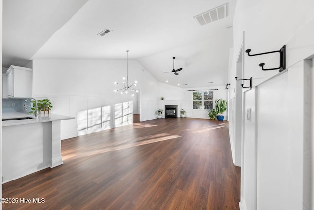 unfurnished living room with dark hardwood / wood-style flooring, ceiling fan with notable chandelier, lofted ceiling, and sink