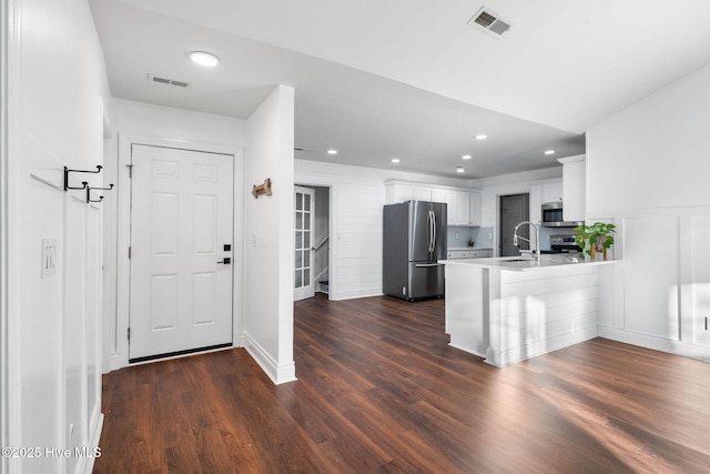 kitchen featuring sink, dark wood-type flooring, stainless steel appliances, kitchen peninsula, and white cabinets