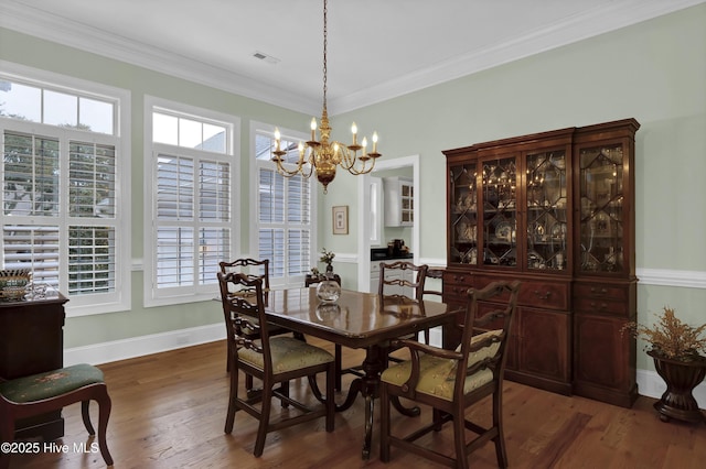 dining room featuring dark wood-type flooring, crown molding, and a chandelier