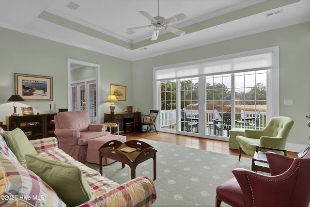 living room featuring crown molding, plenty of natural light, and a tray ceiling