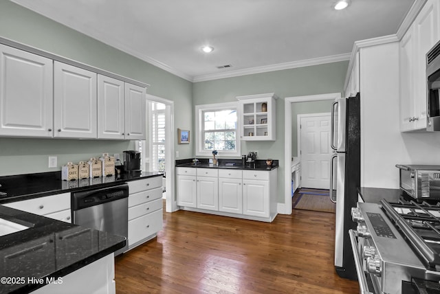 kitchen featuring white cabinetry, dark stone countertops, stainless steel appliances, crown molding, and dark wood-type flooring