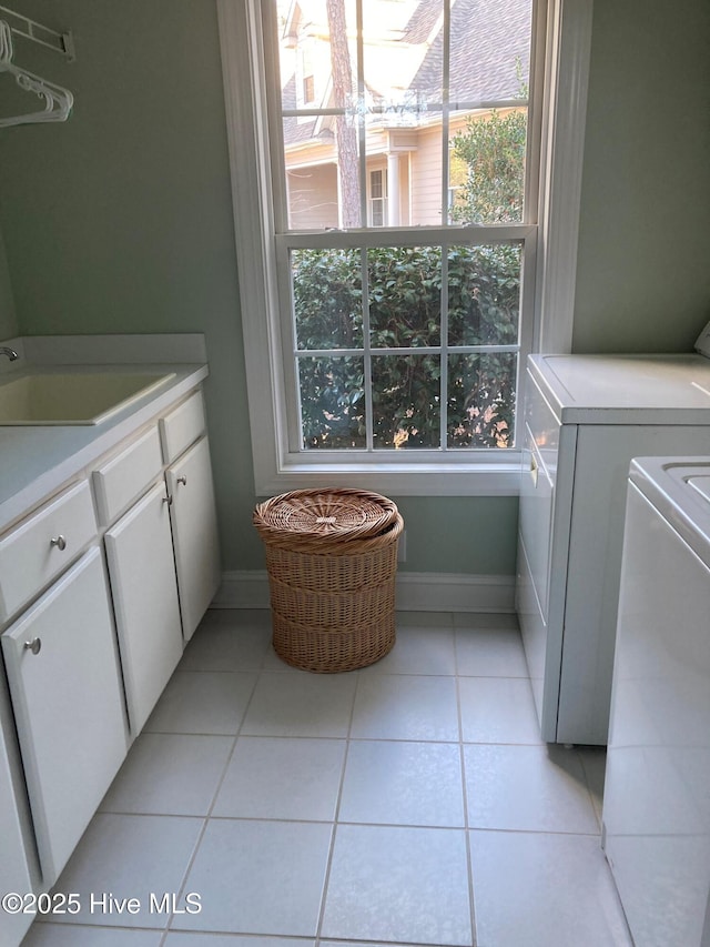 clothes washing area featuring sink, cabinets, and light tile patterned flooring