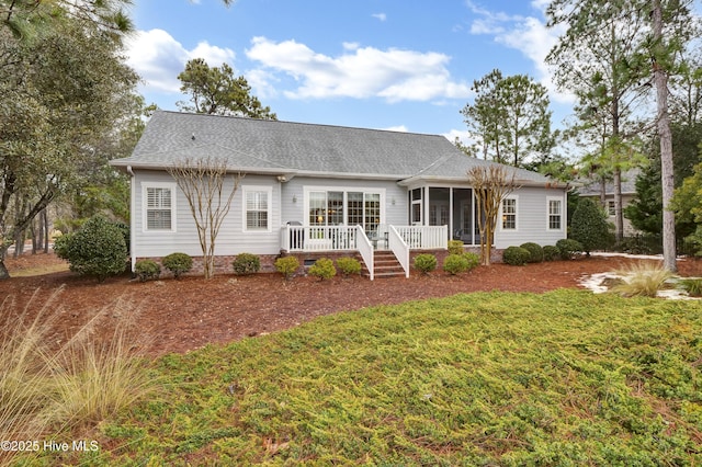 back of property with a wooden deck, a sunroom, and a lawn