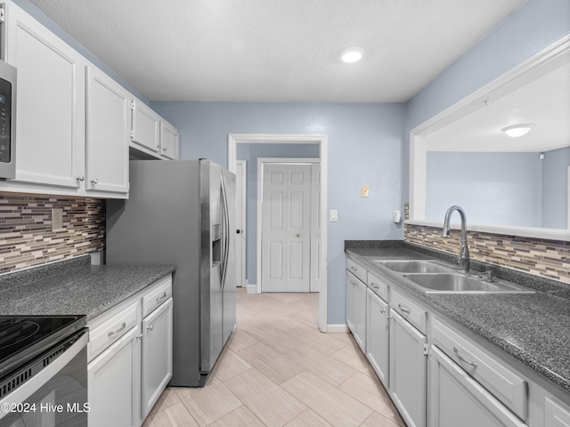 kitchen with backsplash, white cabinets, sink, electric range, and stainless steel fridge