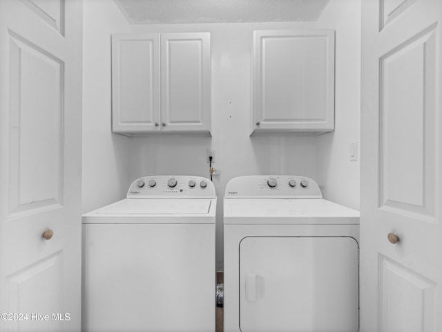 laundry room featuring washer and dryer, cabinets, and a textured ceiling