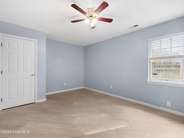 spare room with a textured ceiling and ceiling fan