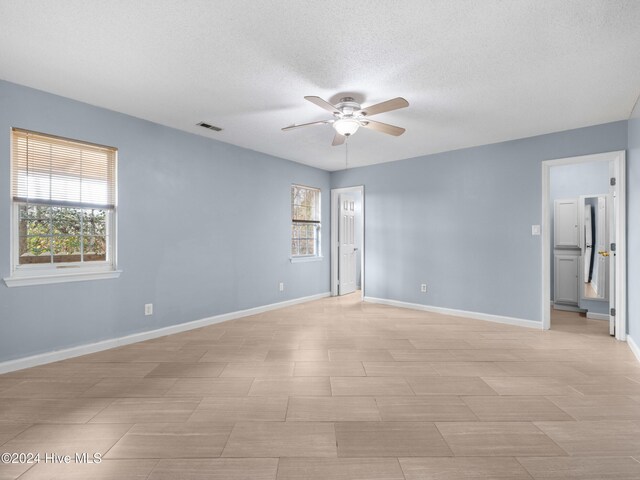 empty room with a textured ceiling and ceiling fan