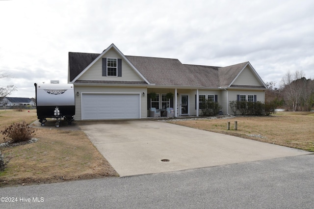 view of front of property featuring covered porch, a garage, and a front lawn