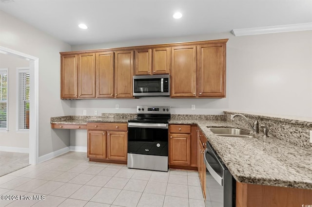 kitchen featuring light tile patterned flooring, stainless steel appliances, light stone counters, and sink