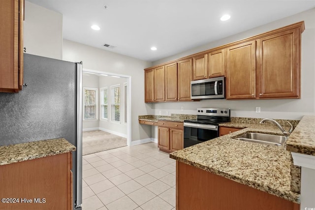 kitchen featuring kitchen peninsula, appliances with stainless steel finishes, light stone counters, sink, and light tile patterned floors