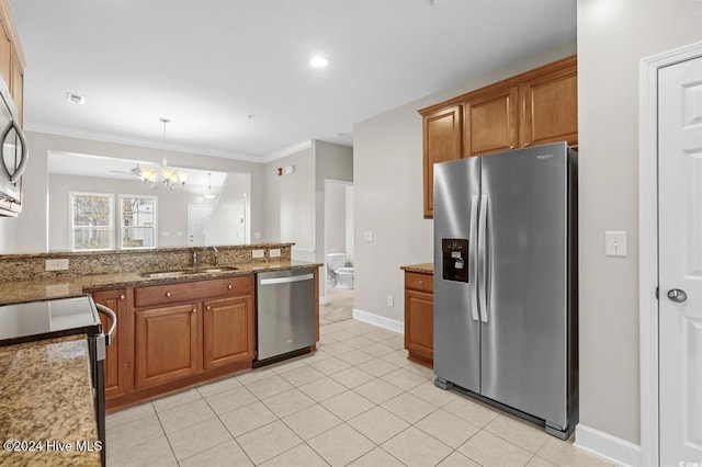 kitchen with light stone countertops, sink, stainless steel appliances, an inviting chandelier, and pendant lighting