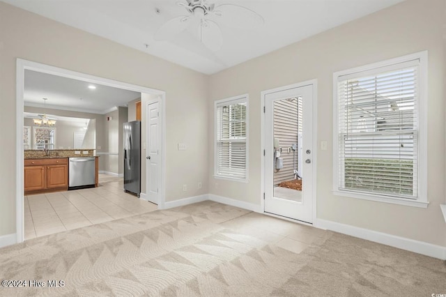 interior space with ceiling fan with notable chandelier, a healthy amount of sunlight, sink, and light carpet