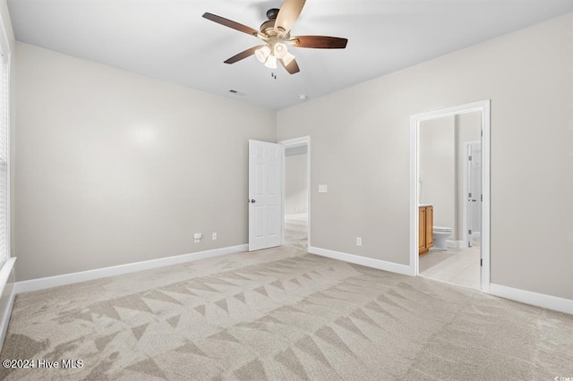 unfurnished bedroom featuring ceiling fan, light carpet, and connected bathroom