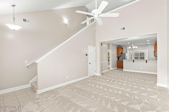 unfurnished living room with high vaulted ceiling, light colored carpet, and ceiling fan with notable chandelier