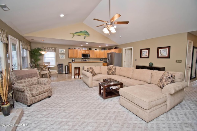 carpeted living room with ceiling fan and high vaulted ceiling