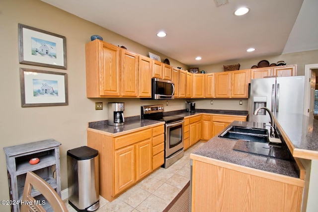 kitchen with light tile patterned floors, stainless steel appliances, light brown cabinetry, and sink