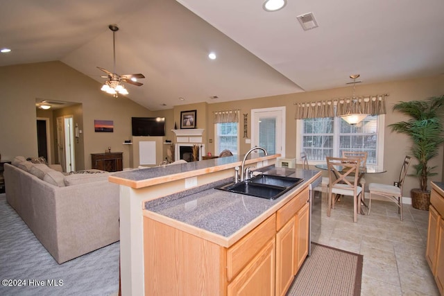 kitchen with sink, vaulted ceiling, ceiling fan, an island with sink, and light brown cabinetry