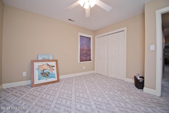 unfurnished bedroom with a closet, light colored carpet, and ceiling fan