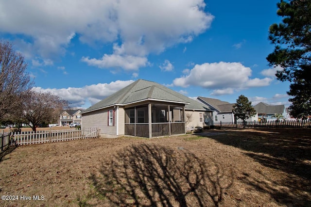 rear view of house featuring a lawn and a sunroom