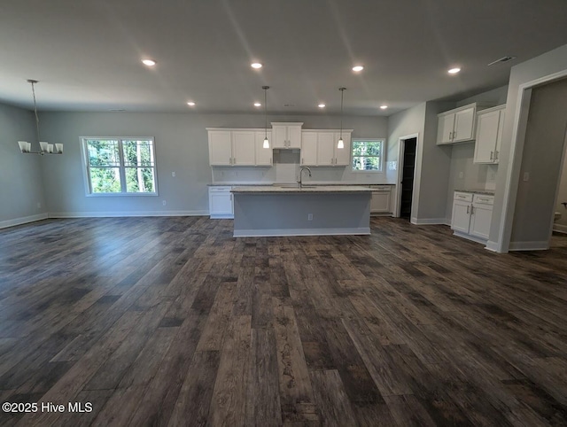 kitchen with white cabinetry, sink, decorative light fixtures, and a kitchen island with sink