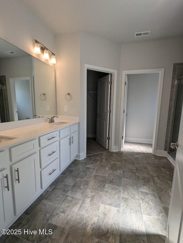 bathroom with a shower with shower door and vanity