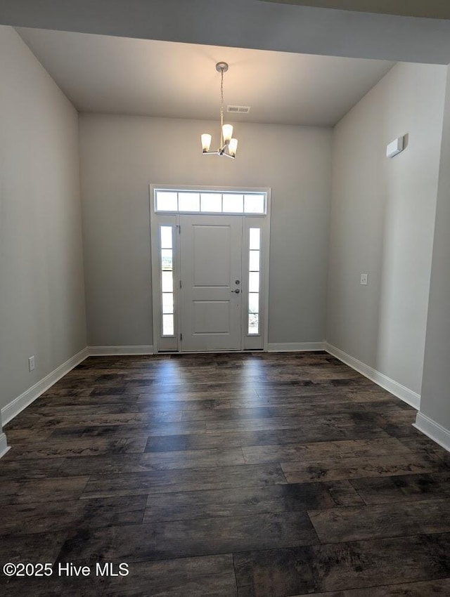 foyer entrance featuring dark wood-type flooring and an inviting chandelier