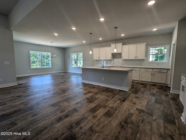 kitchen featuring white cabinetry, an island with sink, hanging light fixtures, a wealth of natural light, and sink