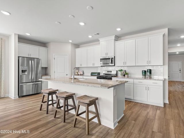 kitchen featuring white cabinets, appliances with stainless steel finishes, a kitchen island with sink, and sink