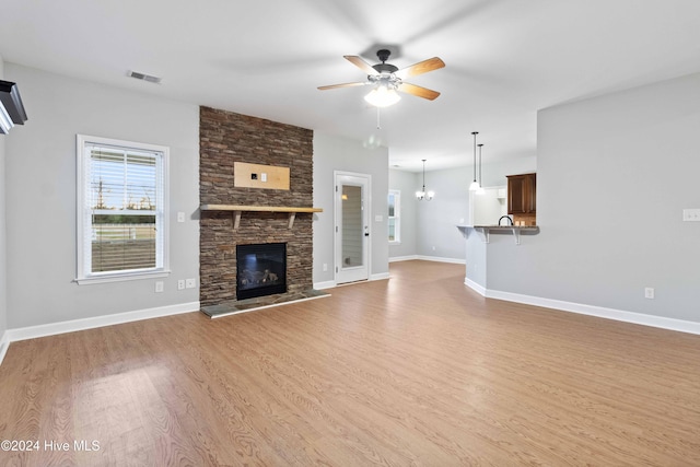 unfurnished living room featuring hardwood / wood-style floors, ceiling fan, and a stone fireplace