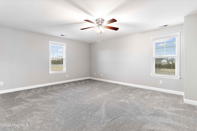 empty room with carpet flooring, ceiling fan, and a wealth of natural light