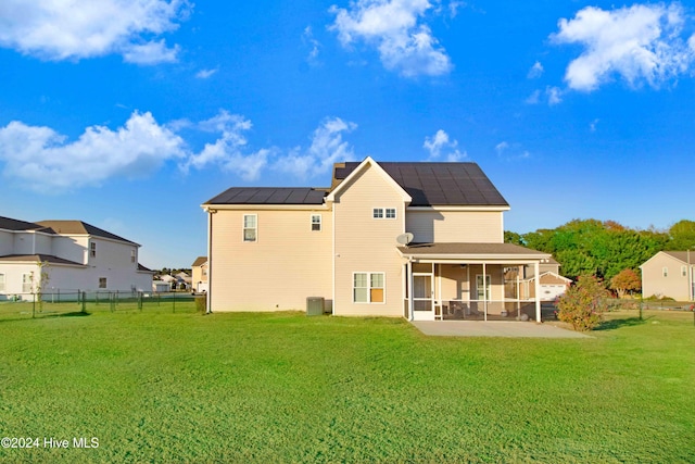 back of house with a sunroom, solar panels, a yard, and central air condition unit