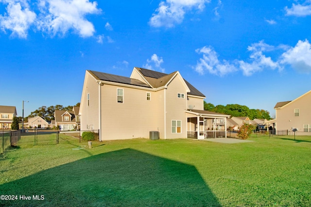 back of property featuring a lawn, a sunroom, and central AC