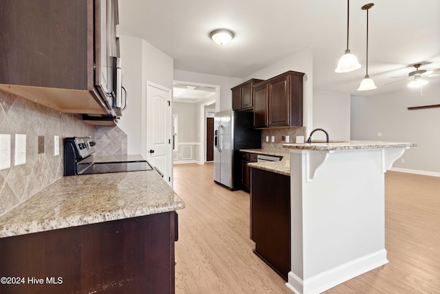 kitchen with tasteful backsplash, stainless steel refrigerator with ice dispenser, stove, light hardwood / wood-style floors, and decorative light fixtures