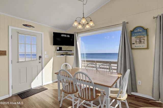 dining space featuring hardwood / wood-style flooring, crown molding, lofted ceiling, and an inviting chandelier