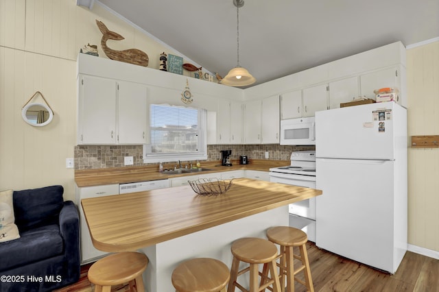 kitchen with pendant lighting, white appliances, wooden counters, white cabinets, and vaulted ceiling