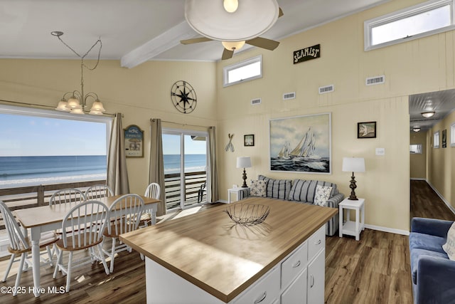 kitchen with dark hardwood / wood-style floors, decorative light fixtures, a view of the beach, white cabinetry, and a water view