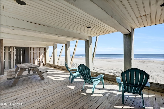 wooden terrace featuring a water view and a beach view