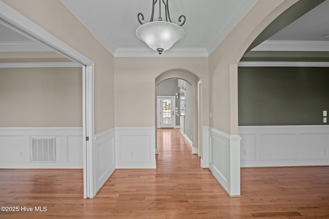 hallway with light wood-type flooring and crown molding