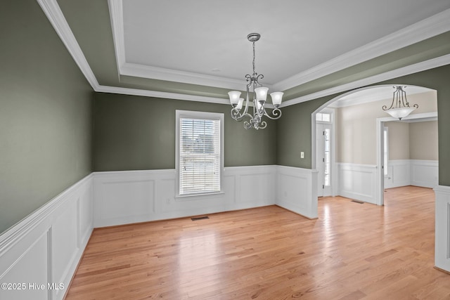 spare room with light wood-type flooring, an inviting chandelier, and ornamental molding